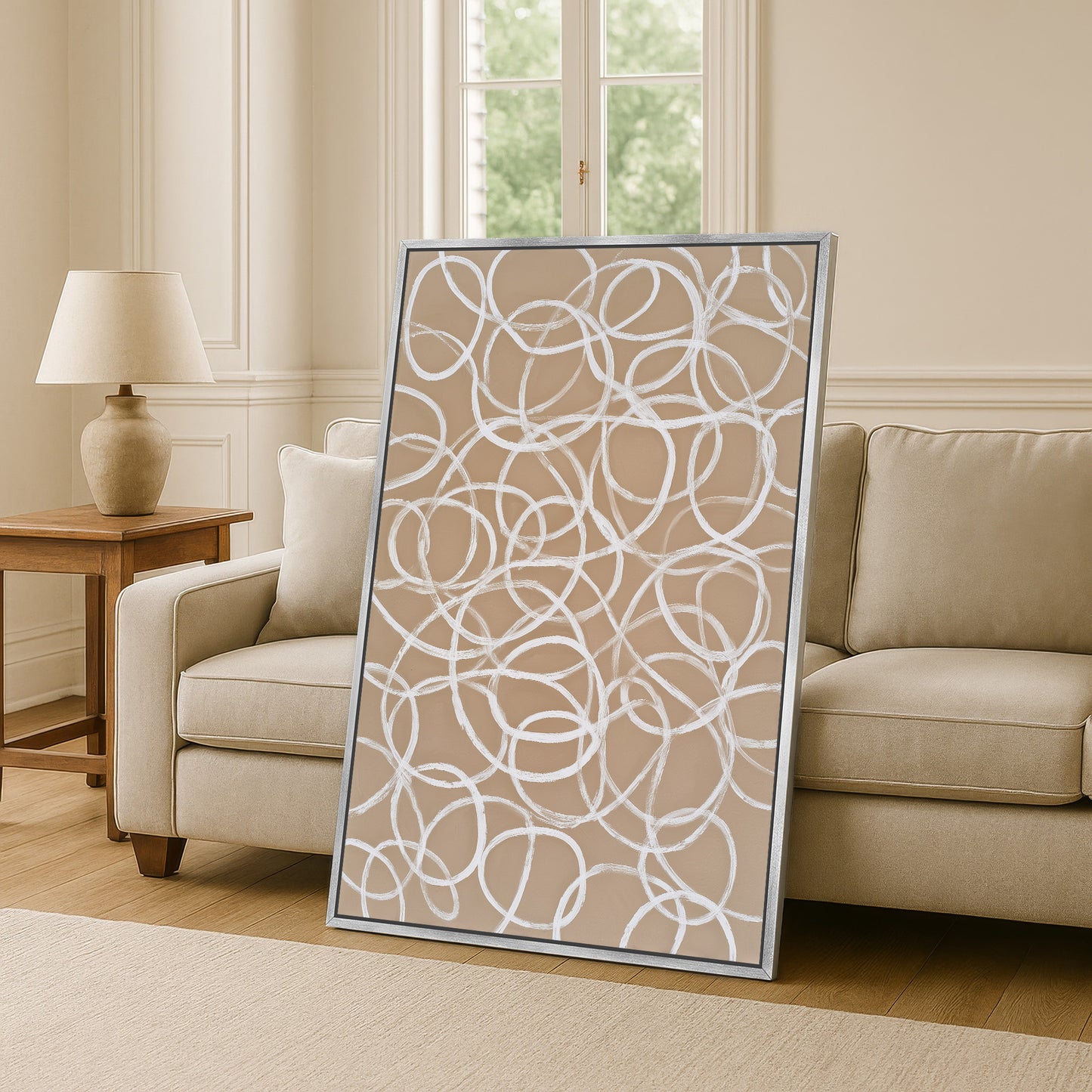 a large abstract painting with a circular pattern on a beige wall, placed in a living room setting with a couch and a side table.