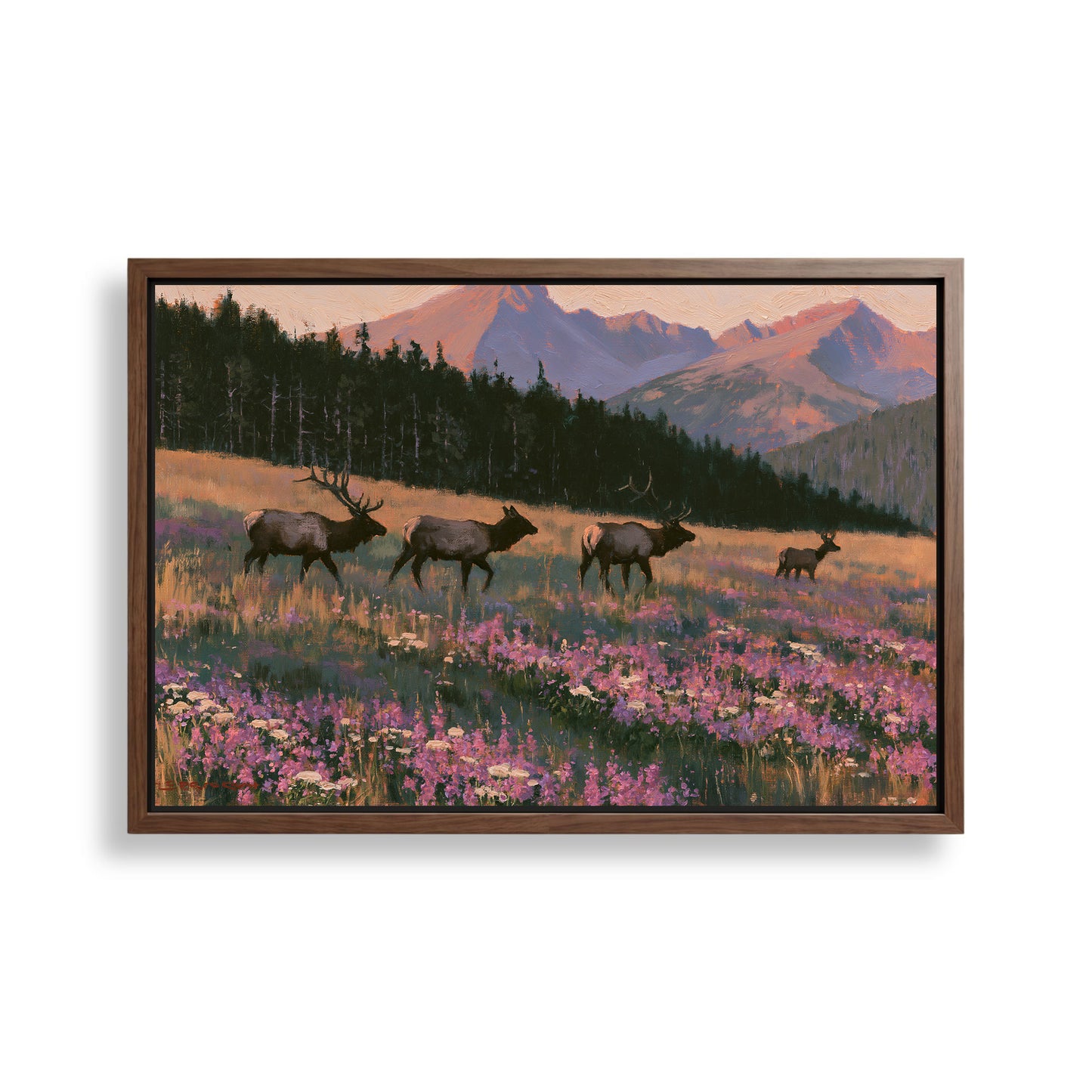 A framed painting depicting a group of elk walking through a field of wildflowers, with mountains in the background.
