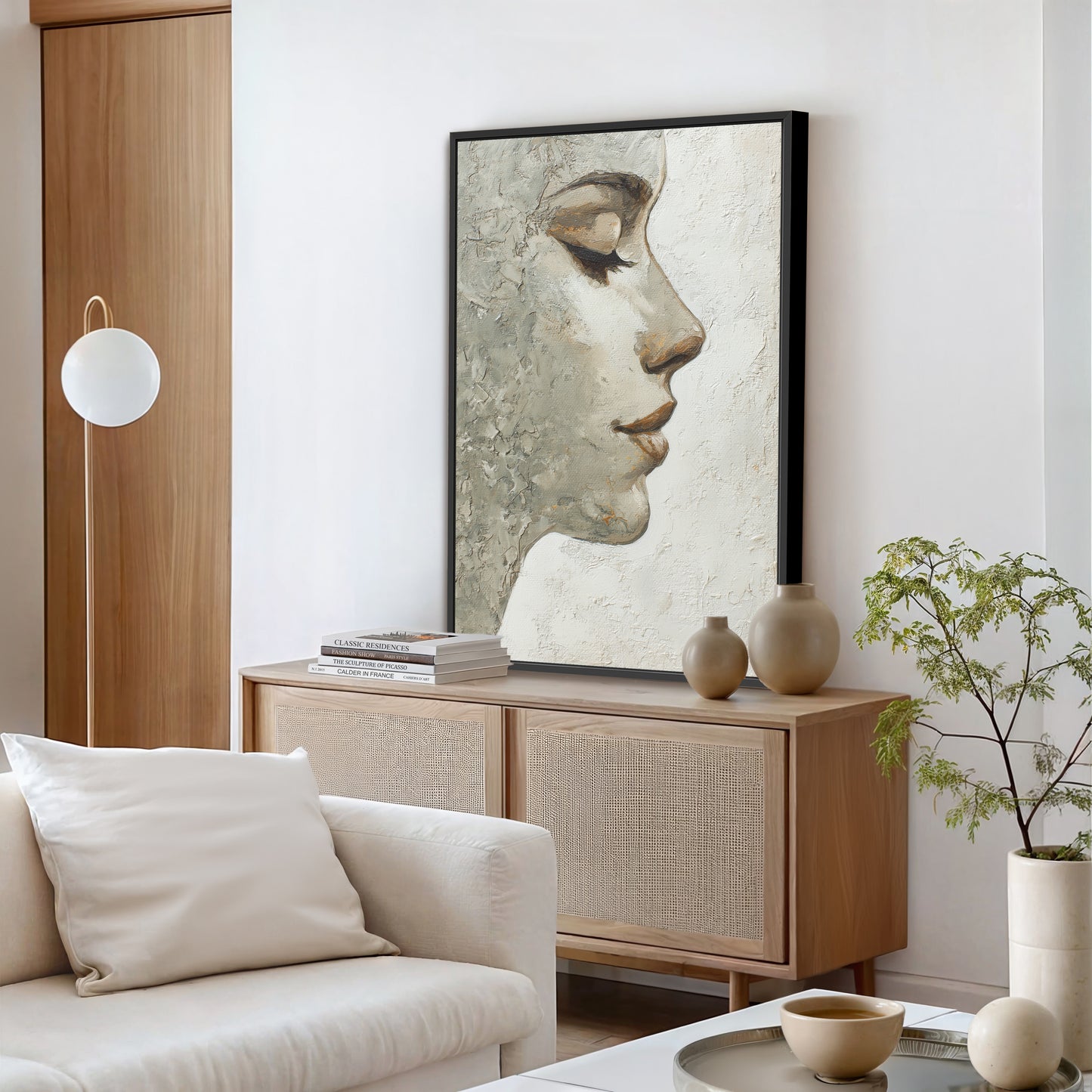 Modern portrait wall art with black frame above console in bright contemporary living room.