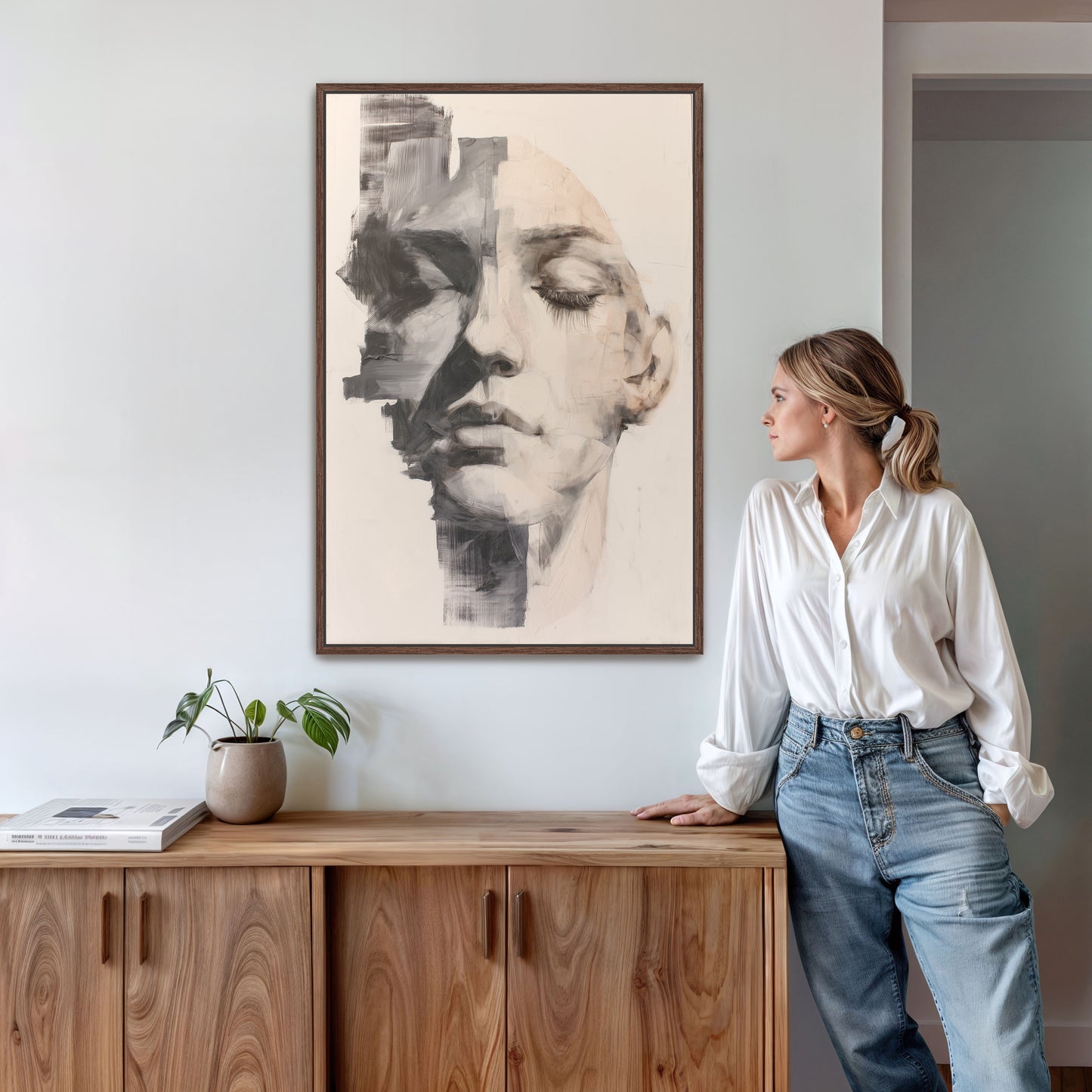 Abstract portrait wall art in walnut brown frame, styled in a modern living space with mid-century wood console and indoor plant.