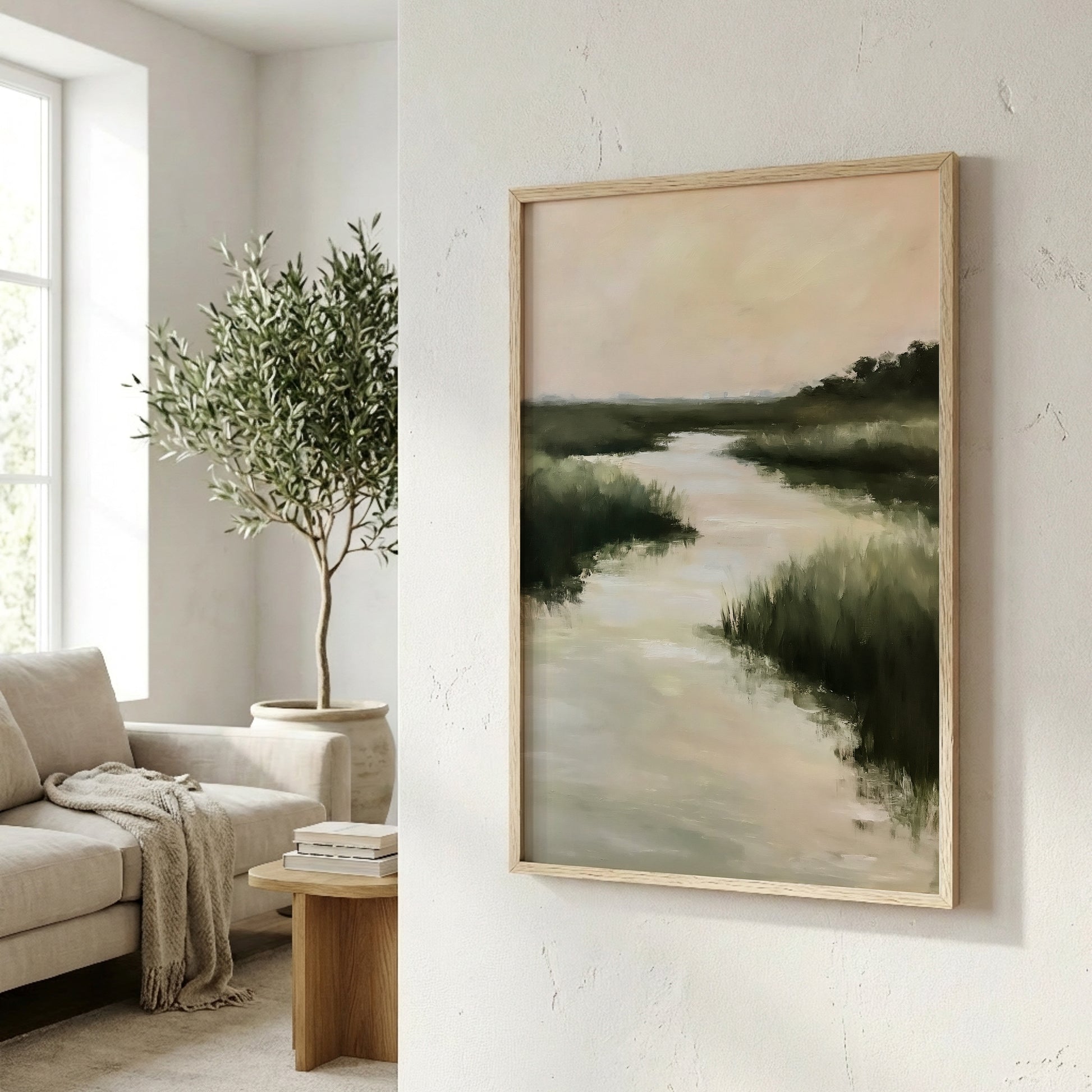 a serene indoor setting with a large painting of a landscape depicting a river and lush greenery hanging on a white wall. In the foreground, there is a comfortable couch and a wooden coffee table with a stack of books on it. A potted plant is also present in the room, adding a touch of nature to the space.