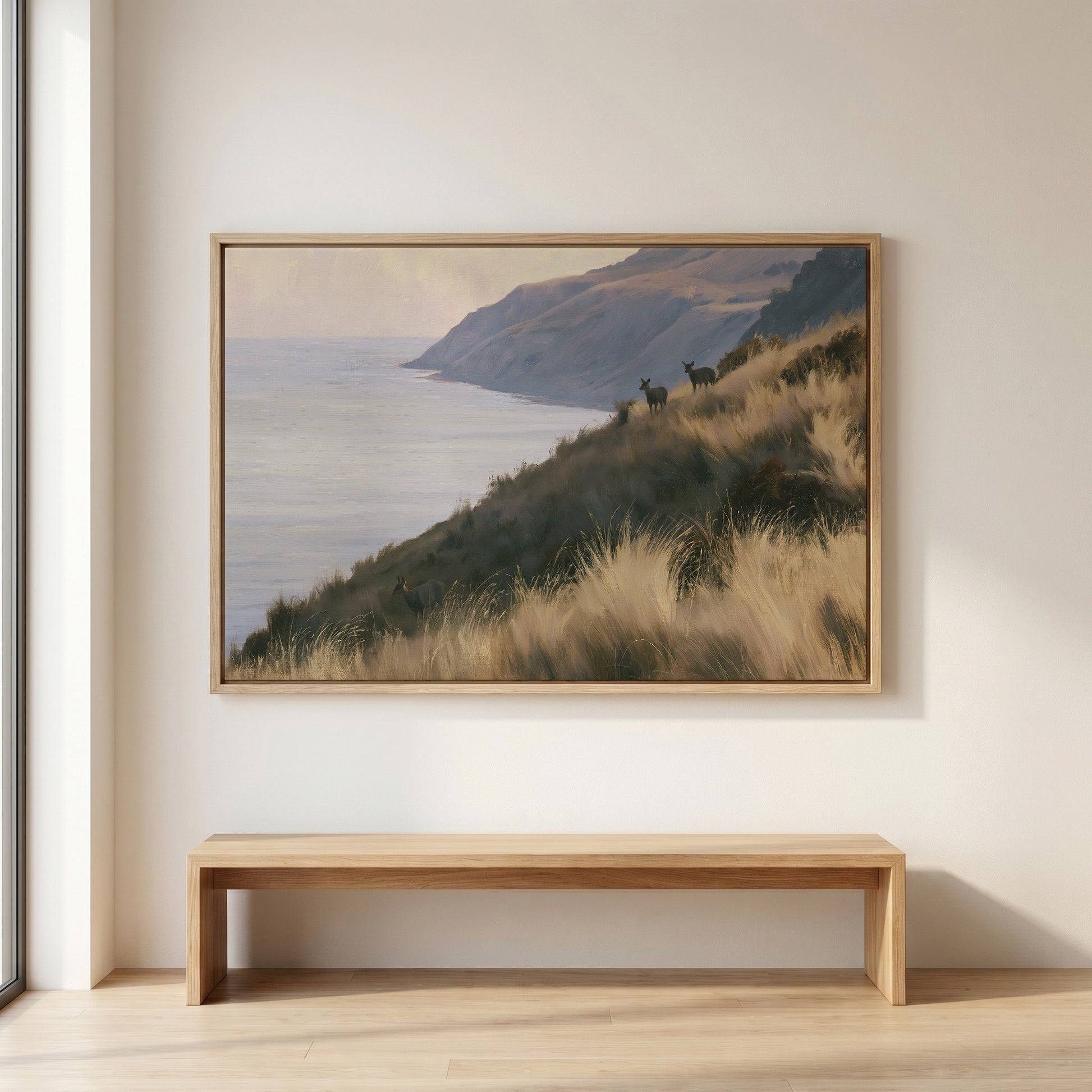 a large painting of a serene landscape with a grassy hill overlooking the ocean, mounted on a wall above a wooden bench.