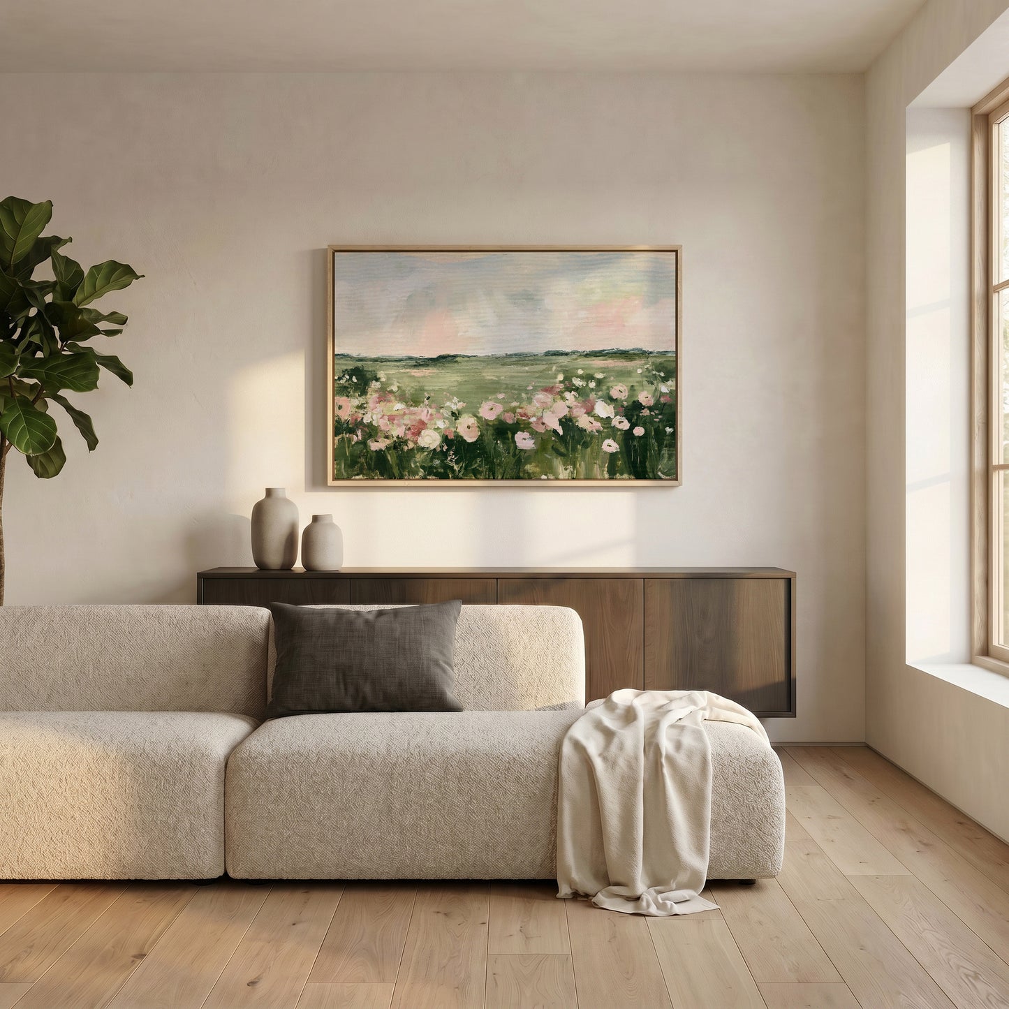 a serene living room with a large painting of a field of flowers hanging on the wall above a beige sofa. The sofa is adorned with a gray throw blanket and a white vase, adding a touch of elegance to the space. The room is illuminated by natural light coming through a window, creating a warm and inviting atmosphere.