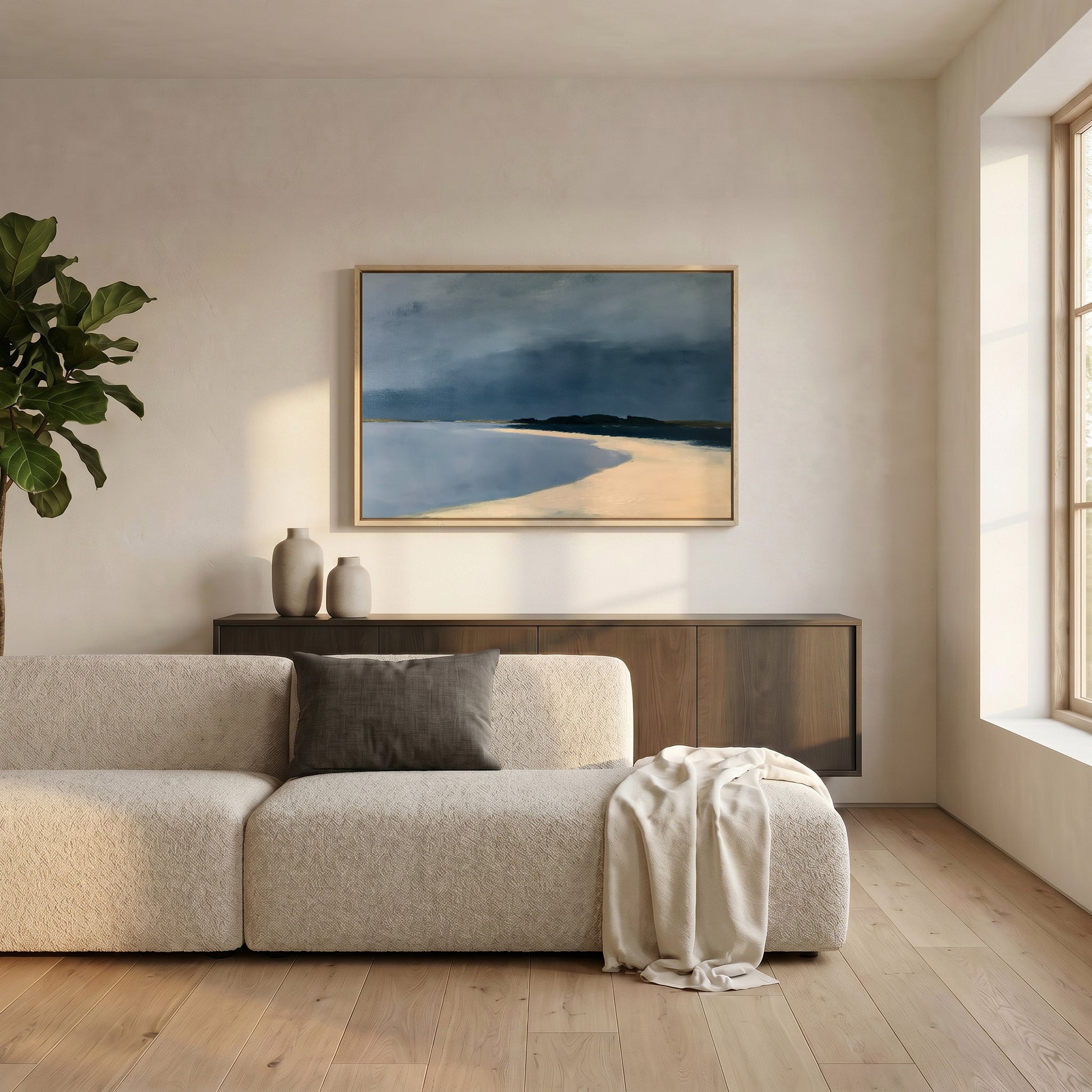 a serene living room with a large window, a white sofa, a wooden cabinet, and a framed painting of a beach scene hanging on the wall.