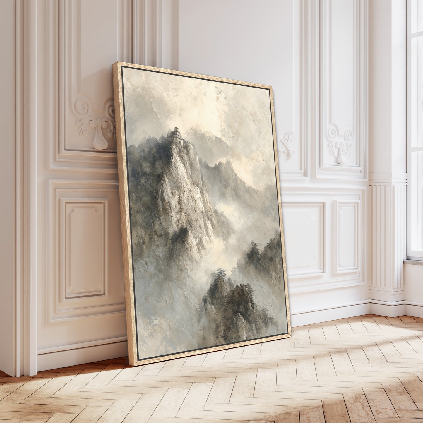 a large, framed painting of a mountainous landscape, leaning against a white wall in a room with a wooden floor.