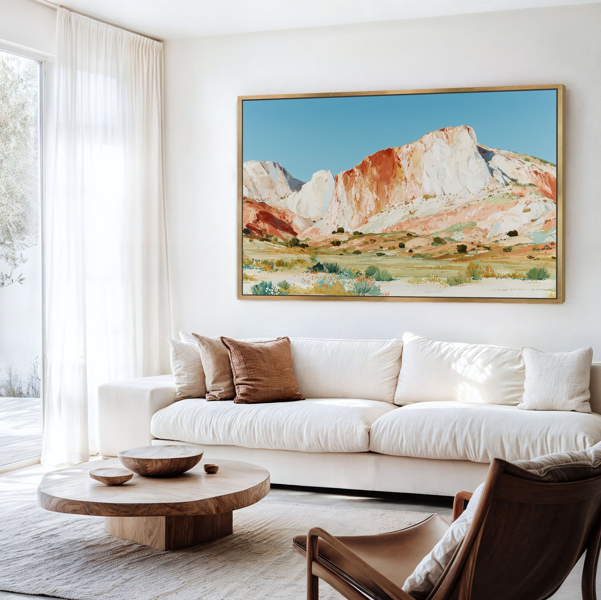 a living room with a large, colorful painting of a mountain landscape hanging on the wall above a white sofa. The sofa is positioned in front of a wooden coffee table, and a brown leather armchair is located nearby. The room has a bright and airy atmosphere, with natural light coming in through a window.