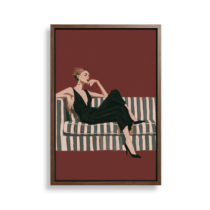 A woman in a black dress is sitting on a striped couch against a red background.