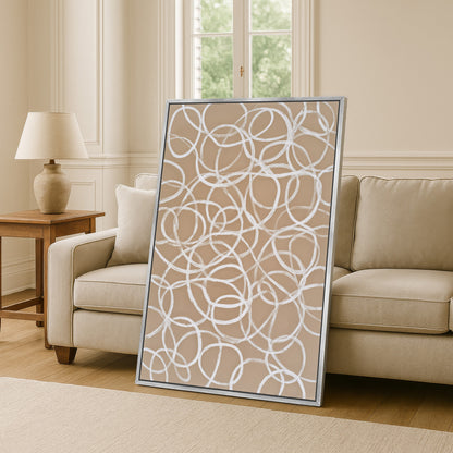 a large abstract painting with a circular pattern on a beige wall, placed in a living room setting with a couch and a side table.