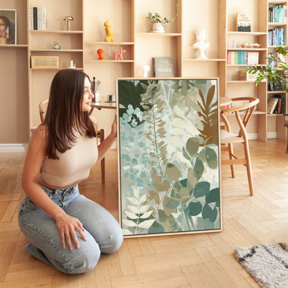 Woman kneeling beside Herba Canvas Print with botanical leaves in sage, sea-green, and beige tones in modern living room