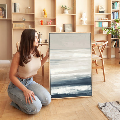 Woman holding Syd canvas print featuring layered ivory, sand, and indigo sea-inspired abstract art in modern living room