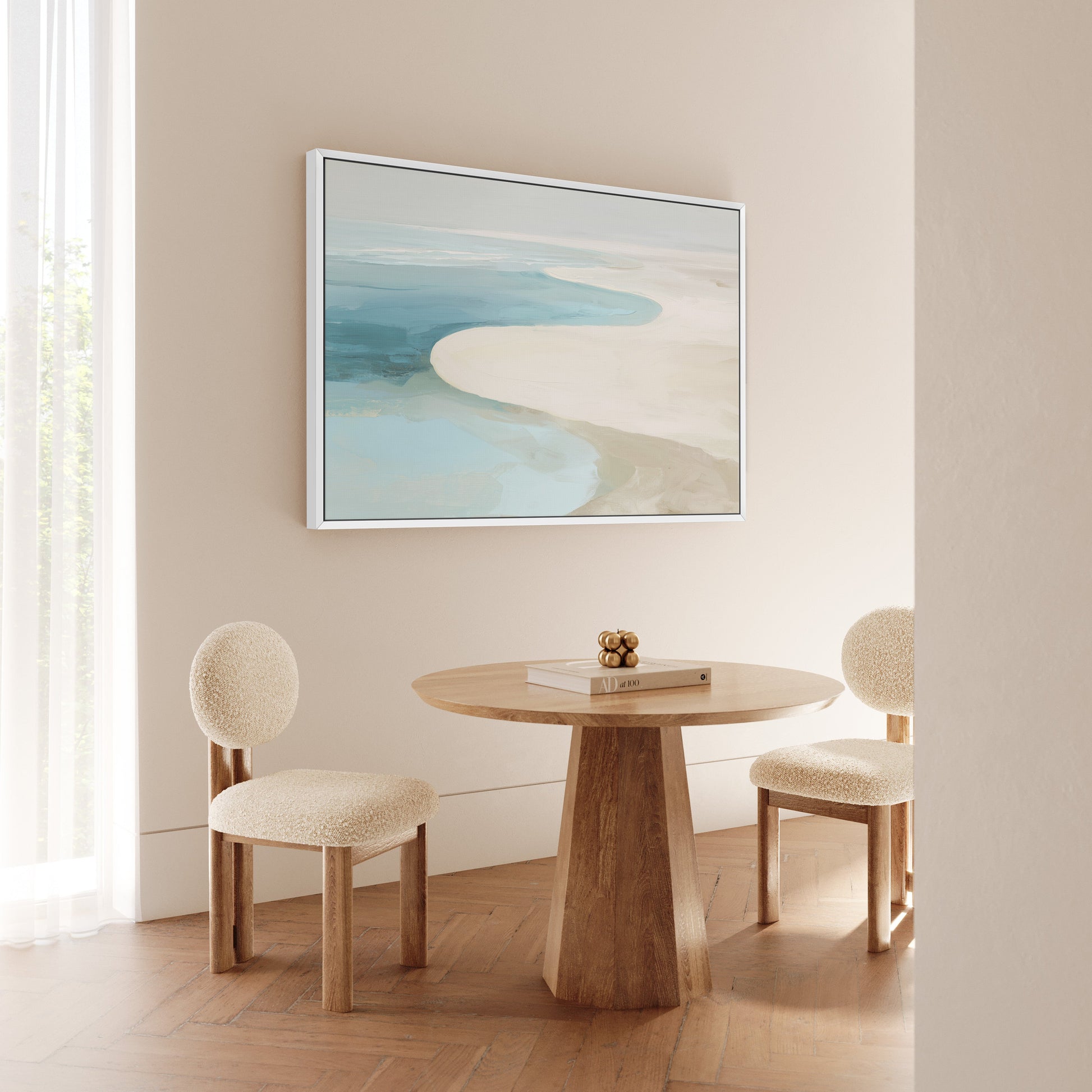 Tideway Canvas Wall Art depicting serene coastal horizon in soft ivory, beige, and ocean blue, framed in white and displayed above a wooden table with two beige upholstered chairs.