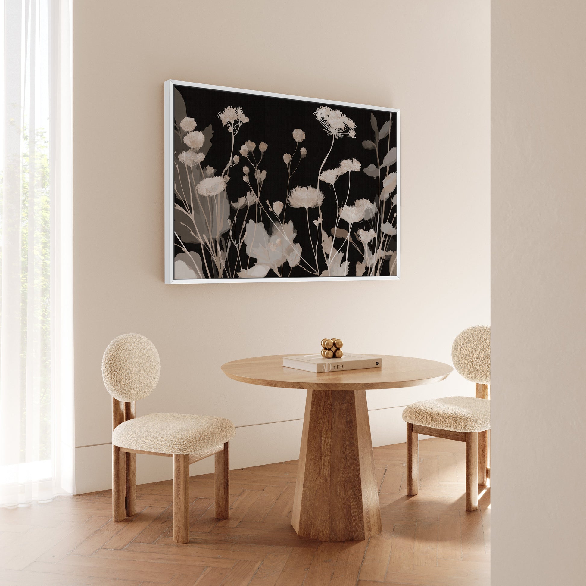 Shadow Bloom Canvas Art featuring neutral wildflowers on black background in a white frame above a wooden table and two chairs in a minimalist room