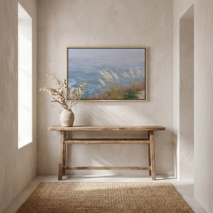 a serene indoor setting with a wooden console table, a vase of dried flowers, and a framed painting of a tranquil landscape above it.