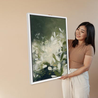 Woman holding framed Verdure canvas wall art with ivory leaves and deep green tones in white frame
