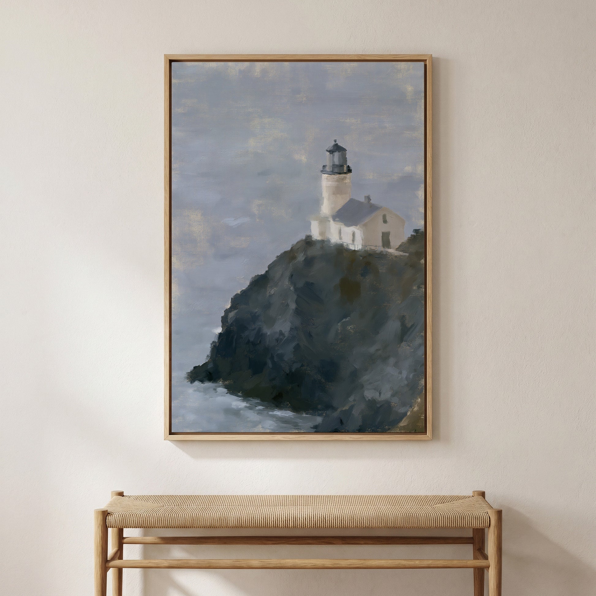 a framed painting of a lighthouse on a cliff, hanging on a wall above a bench.