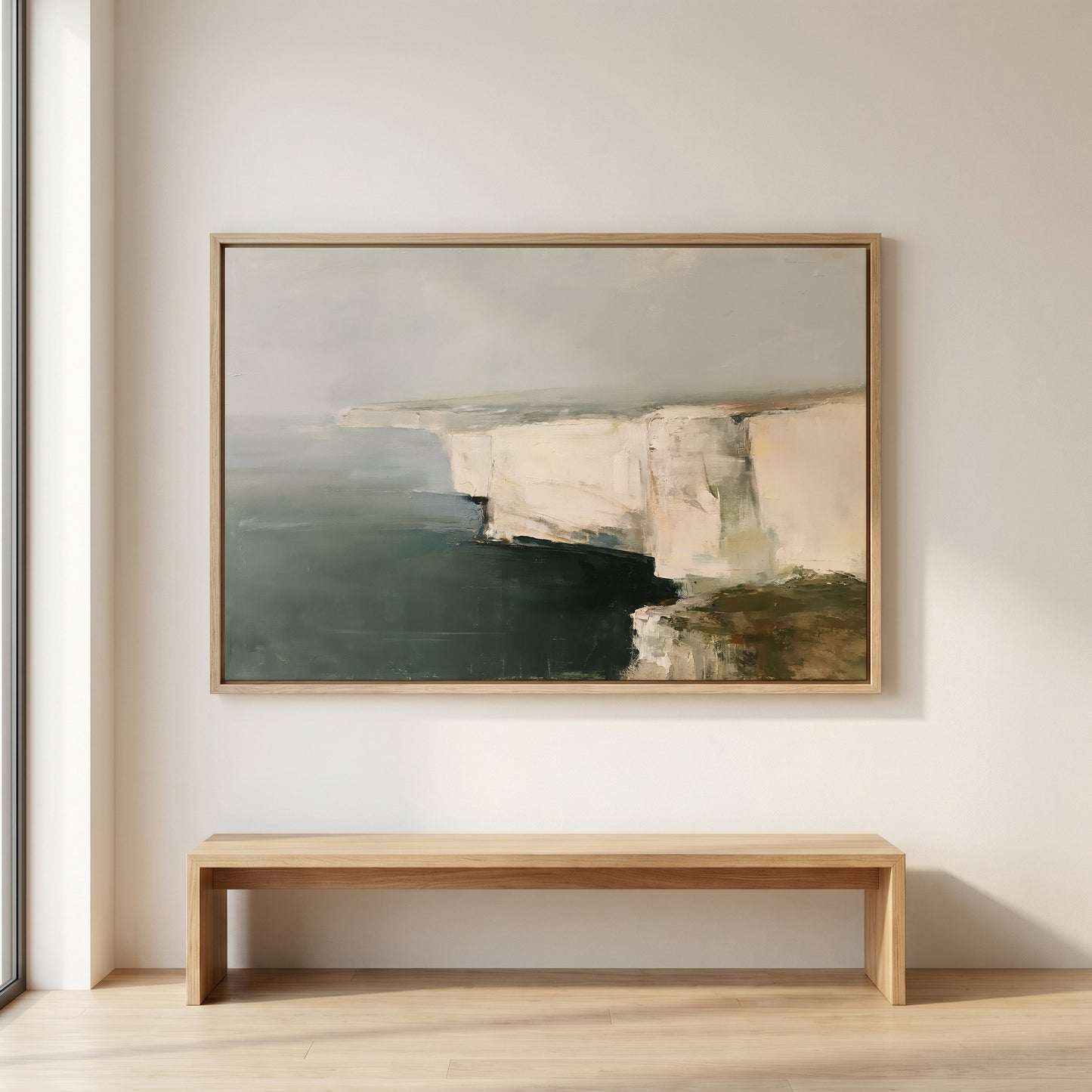 a large painting of a cliff overlooking the ocean, hanging on a white wall above a wooden bench.