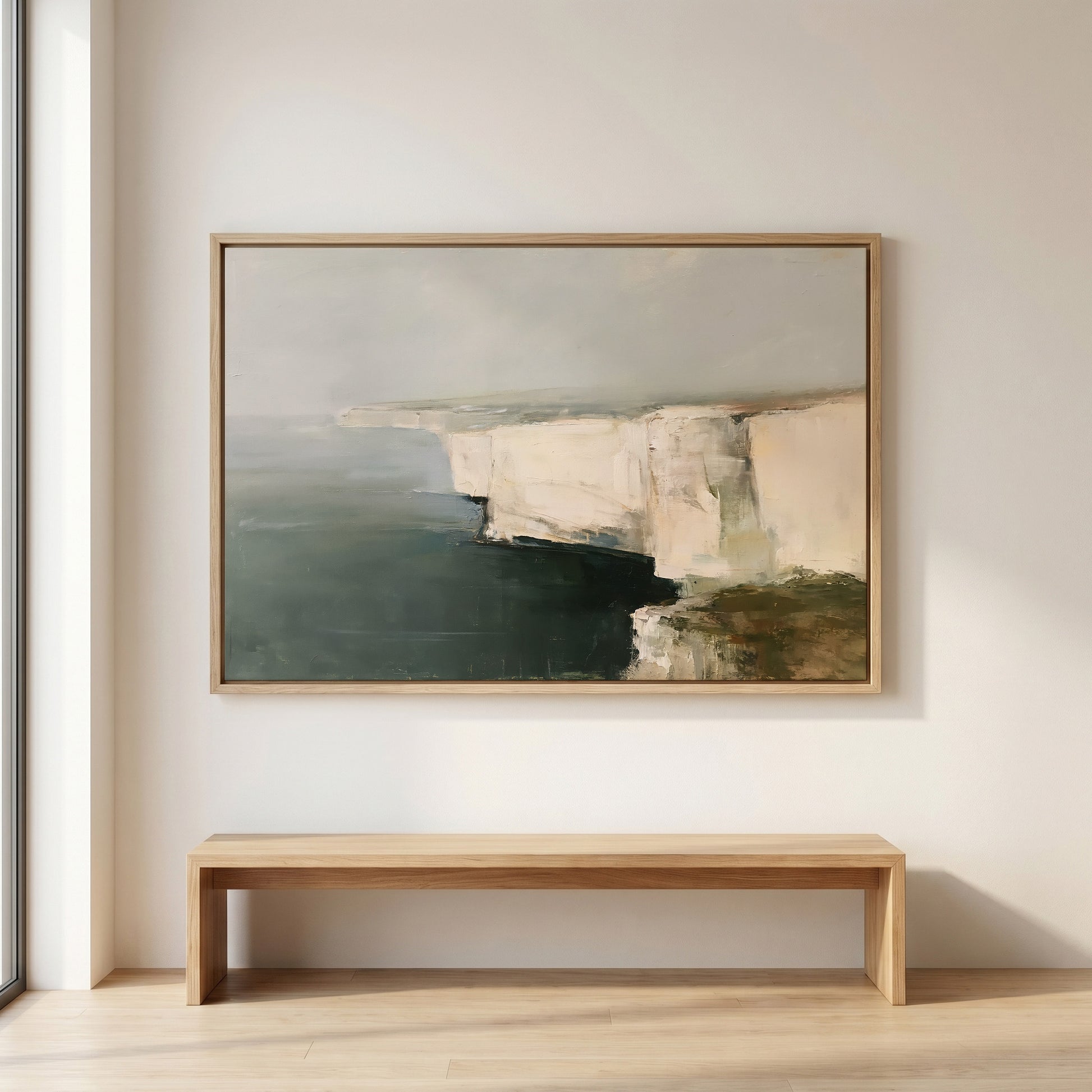 a large painting of a cliff overlooking the ocean, hanging on a white wall above a wooden bench.