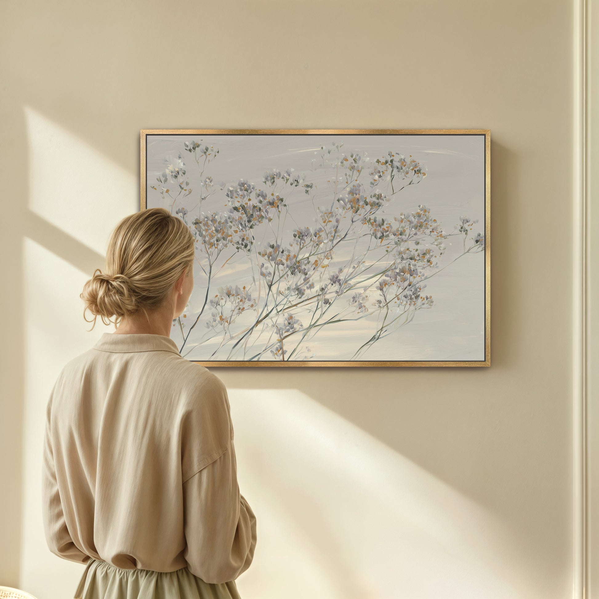 woman observing 'Breeze' Wall Art canvas featuring delicate wildflowers in soft muted tones
