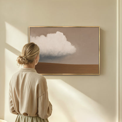 Woman viewing Aerie Canvas Print featuring minimalist cloud and earth horizon in soft taupe and ivory tones