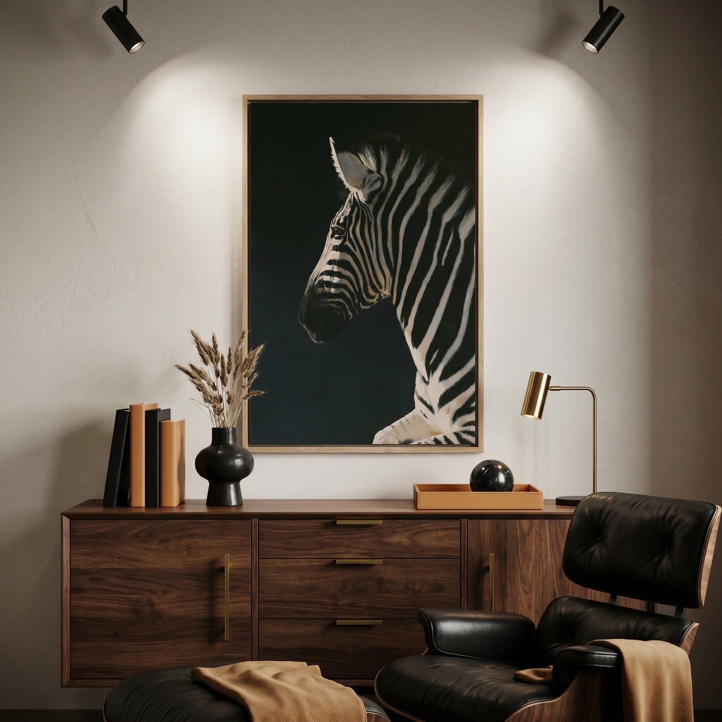 a wooden dresser with a framed painting of a zebra on it, a black leather chair, a wooden side table with a lamp, and a stack of books.