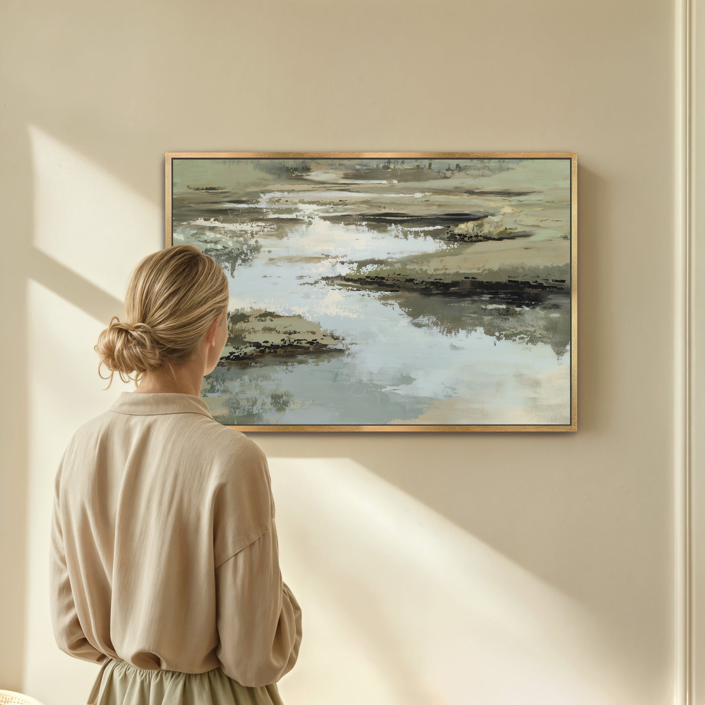 Woman admiring Reed canvas print with layered sage, sand, and ivory tones in a calm, abstract water and earth scene