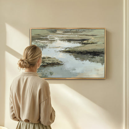 Woman admiring Reed canvas print with layered sage, sand, and ivory tones in a calm, abstract water and earth scene