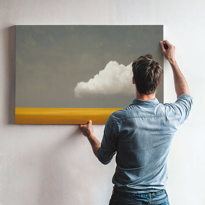 Man hanging Mellow canvas print featuring a white cloud over a golden plain with a muted gray sky.