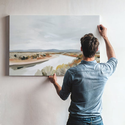 Man hanging Mesa canvas print depicting tranquil modern desert landscape with flowing river and muted earth tones on white wall