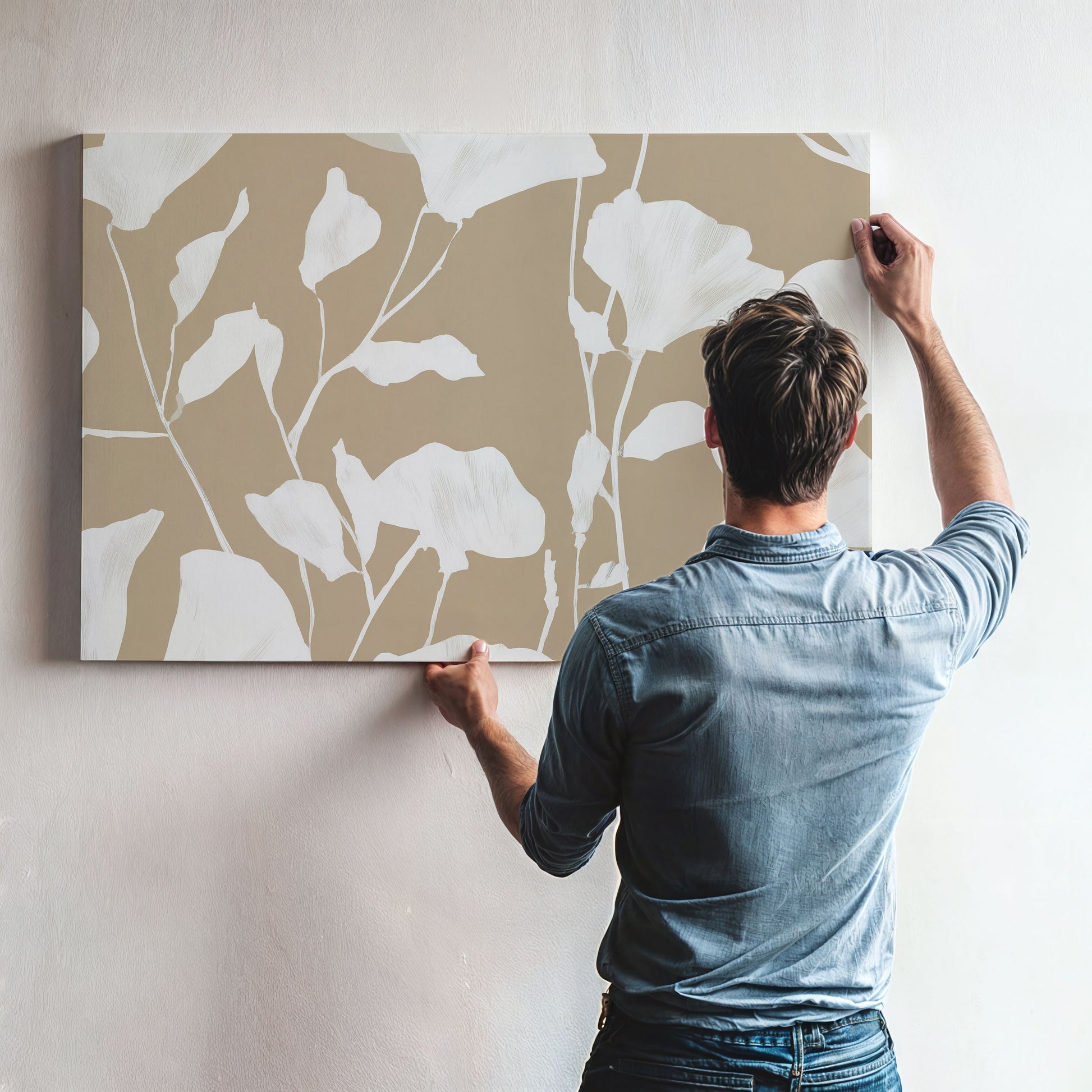 Driftleaf canvas print with soft white floral silhouettes on beige background, displayed by a man on a wall