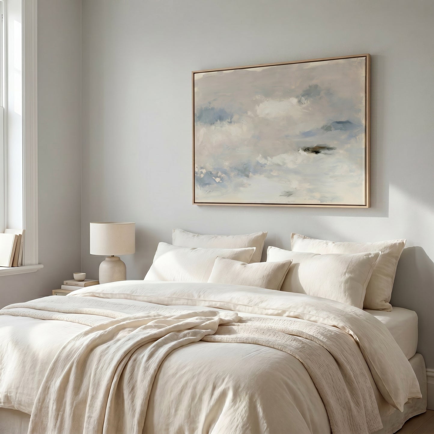 a serene and cozy bedroom with a large bed adorned with white linens and a framed painting of a cloudy sky hanging above it.
