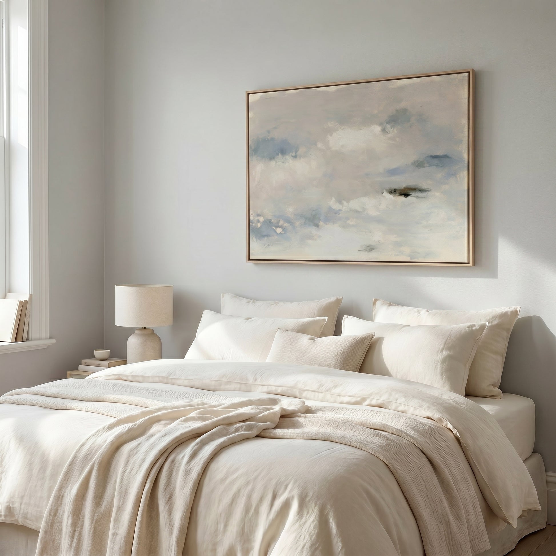 a serene and cozy bedroom with a large bed adorned with white linens and a framed painting of a cloudy sky hanging above it.