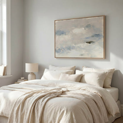 a serene and cozy bedroom with a large bed adorned with white linens and a framed painting of a cloudy sky hanging above it.