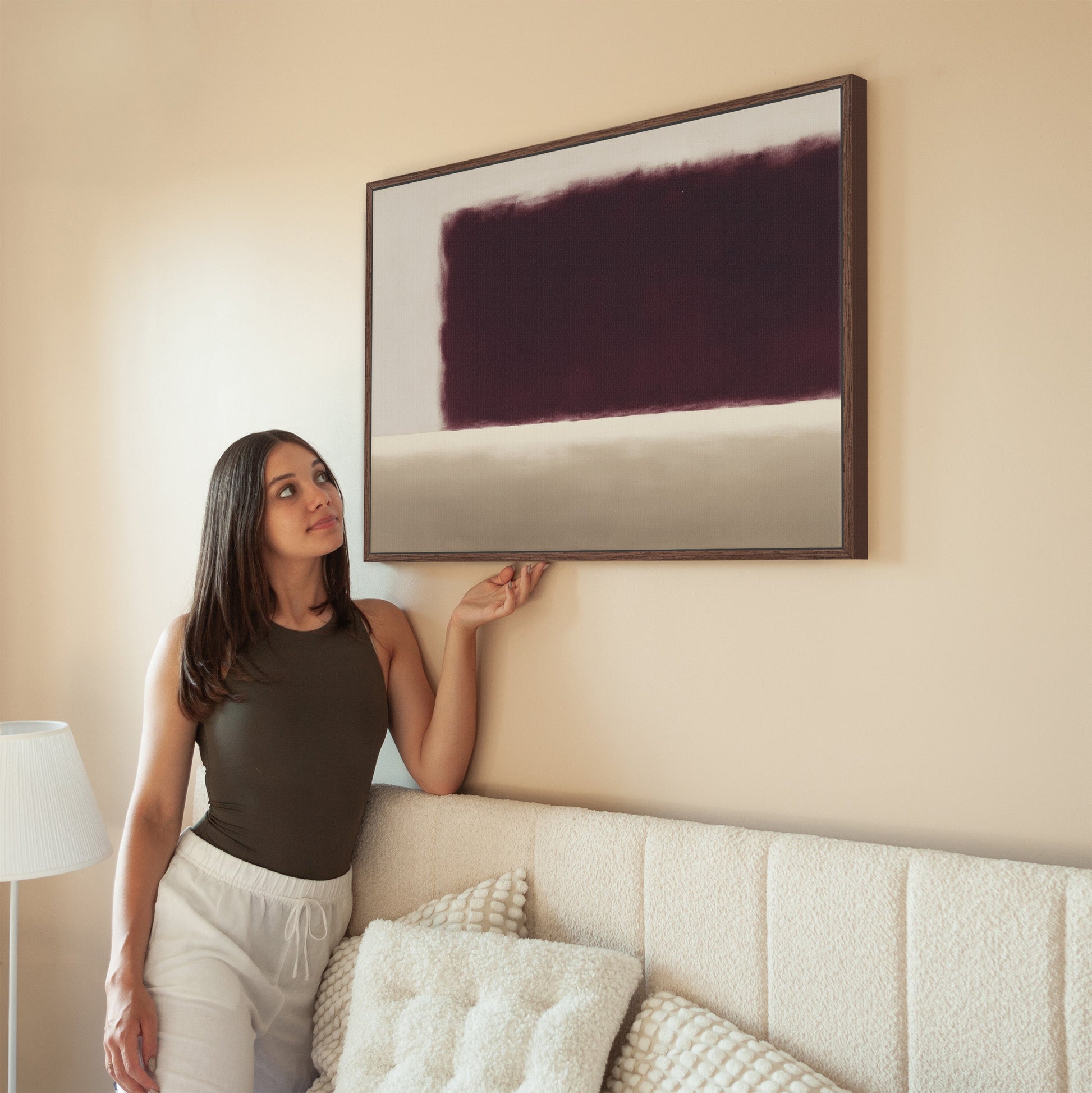 Woman admiring Threshold Canvas Wall Art with deep burgundy and ivory abstract design in modern living room