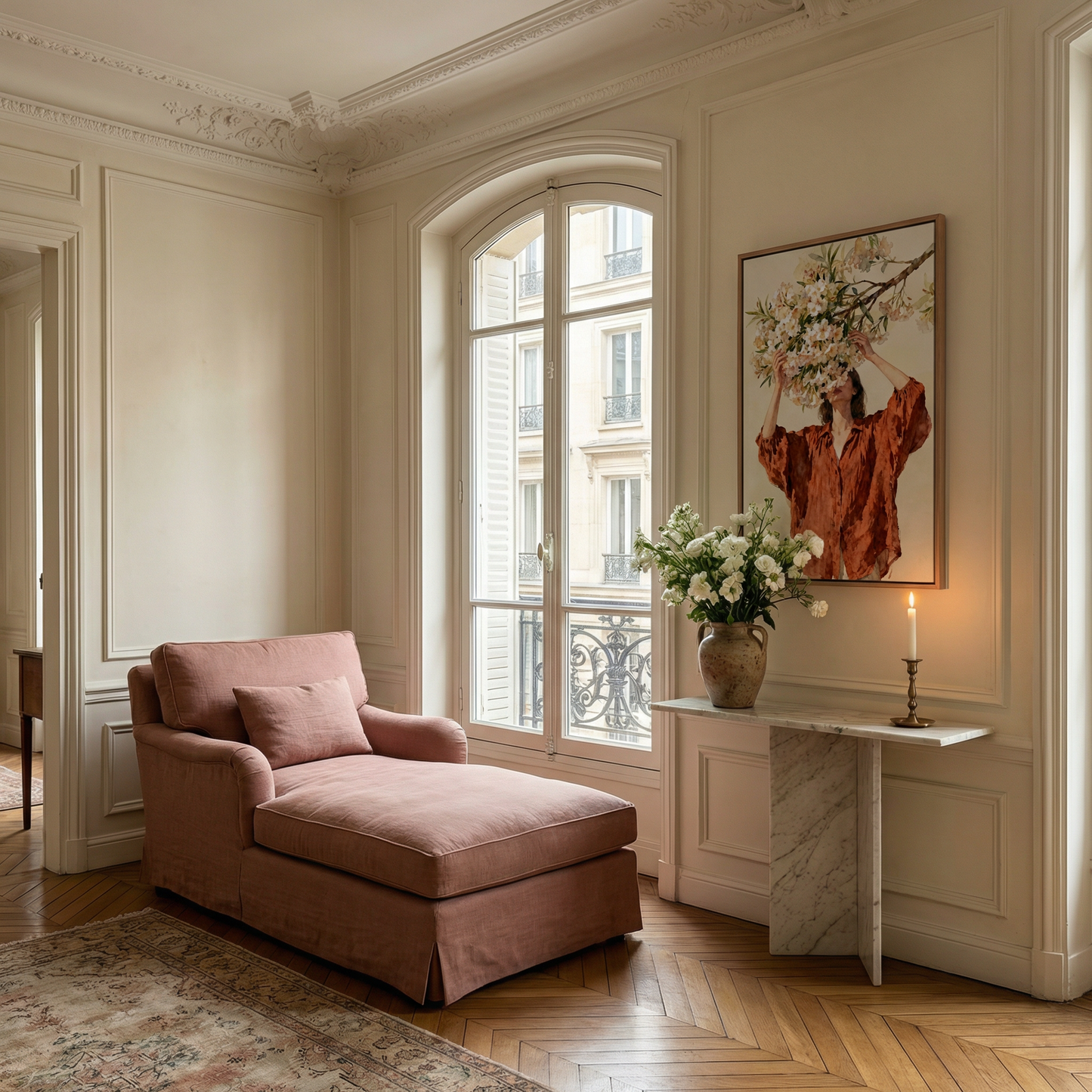 a cozy living room with a plush pink chaise lounge, a white marble side table with a vase of white flowers, and a framed painting of a woman with a floral headpiece. The room has white walls, a large arched window, and a wooden floor.