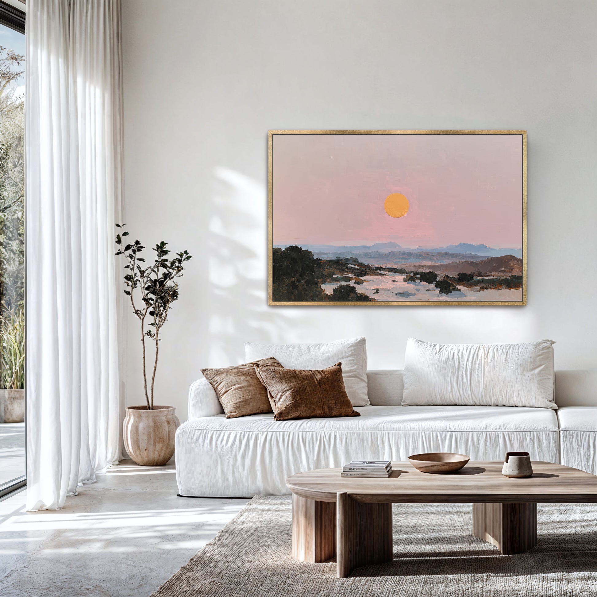 a serene living room with a white sofa, a wooden coffee table, and a large framed painting of a sunset over a mountain landscape hanging on the wall.