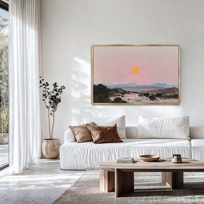a serene living room with a white sofa, a wooden coffee table, and a large framed painting of a sunset over a mountain landscape hanging on the wall.