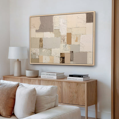 a living room with a large abstract painting hanging on the wall above a wooden cabinet. The cabinet has a bowl and two books on top of it. The room also includes a white couch and a lamp.