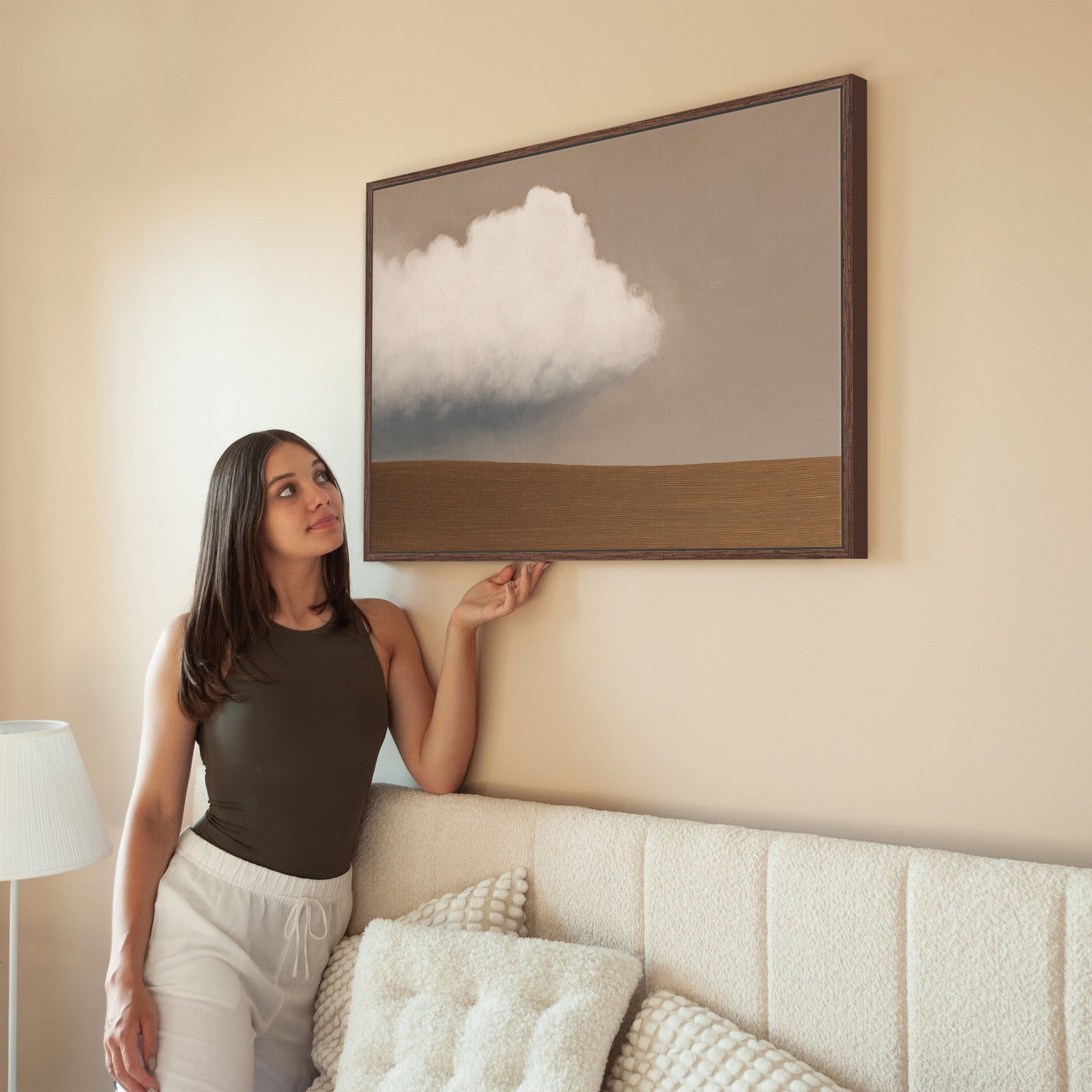 Woman admiring Aerie Canvas Print with minimalist cloud and earth tones in modern interior