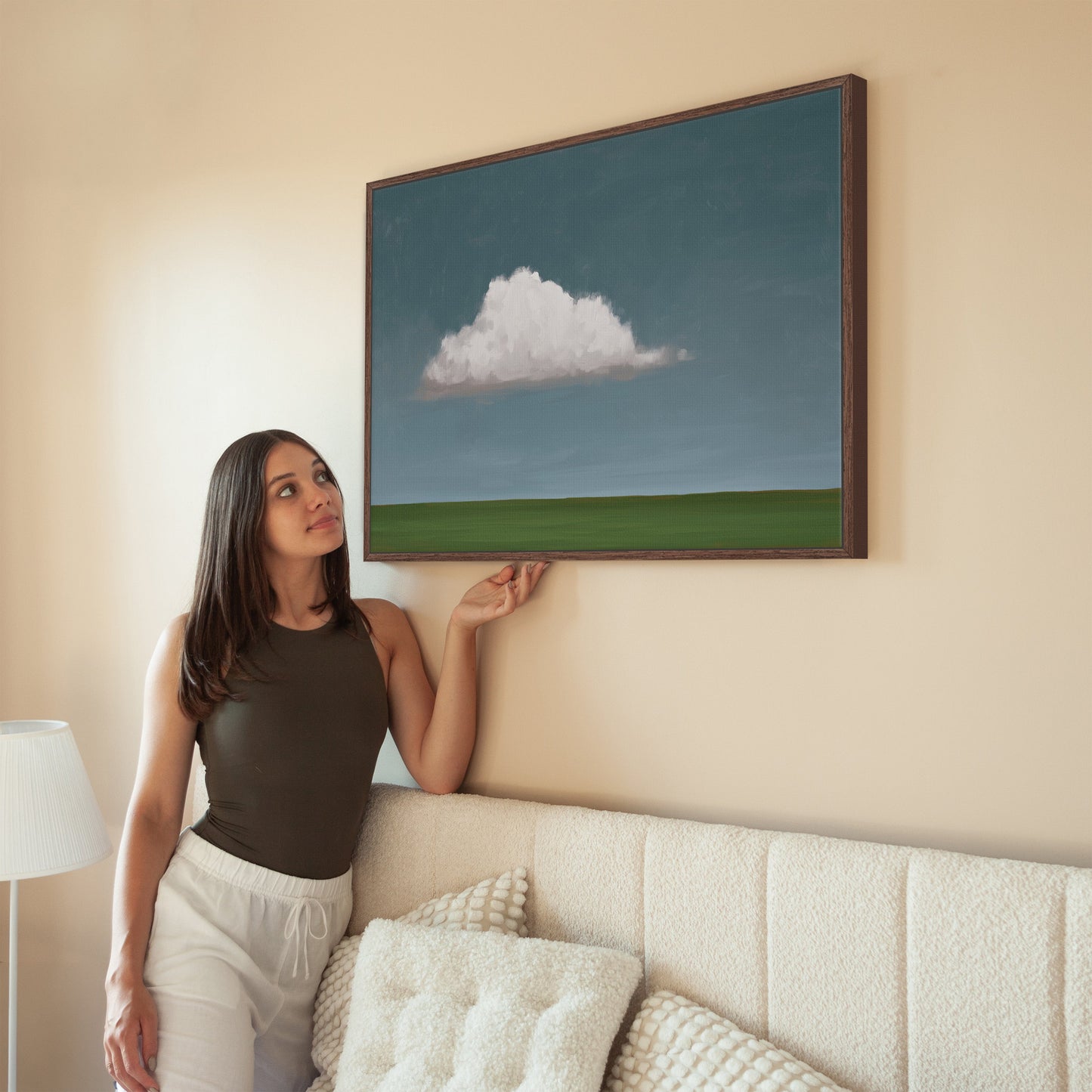 Eave canvas print with single cloud over green horizon in wooden frame hanging on beige wall