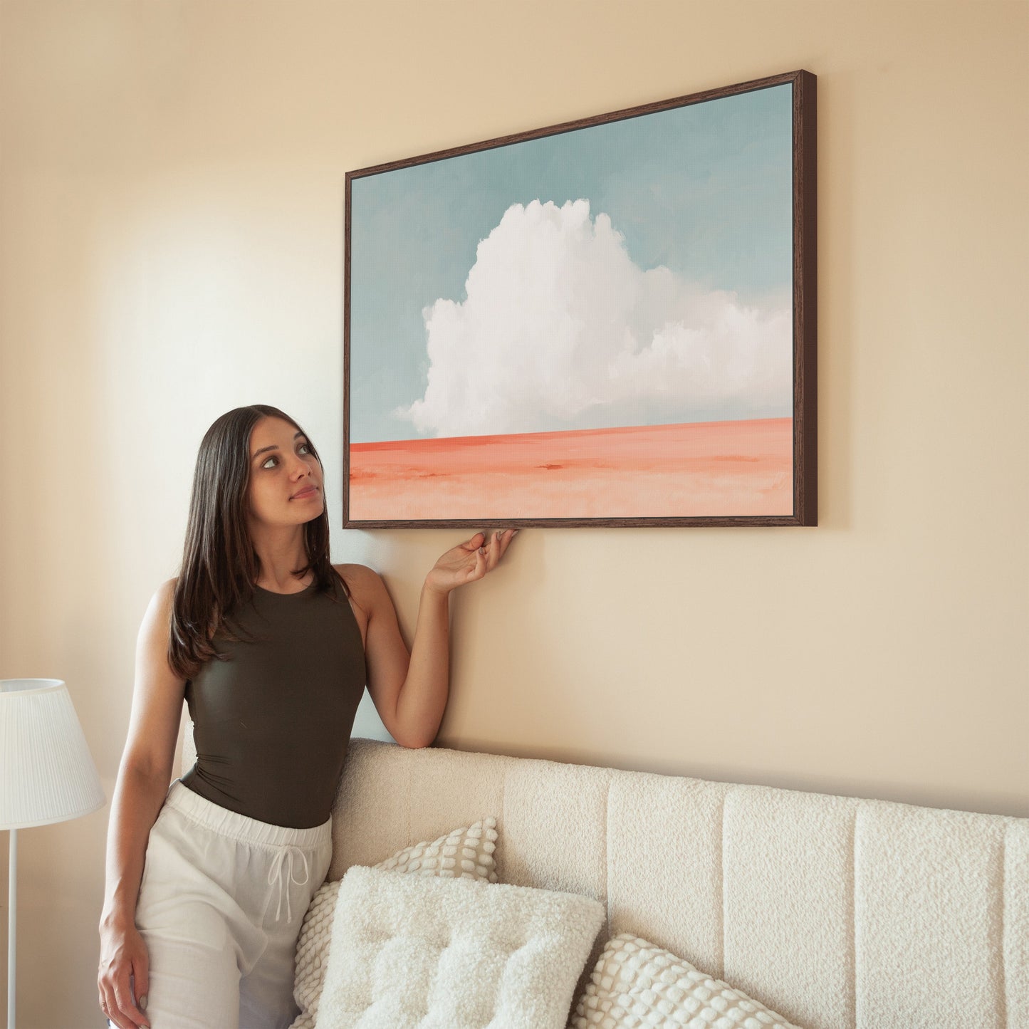 Woman admiring Aurea Canvas Wall Art featuring white cloud over coral horizon in minimalist living room