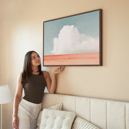 Woman admiring Aurea Canvas Wall Art featuring white cloud over coral horizon in minimalist living room