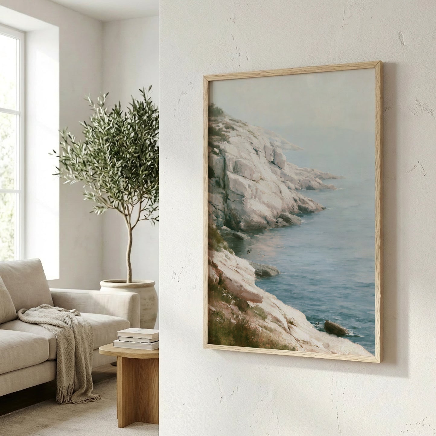 a serene living room with a large framed painting of a rocky coastline and a lush green tree in the corner, creating a calming and natural atmosphere.