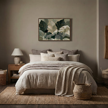 a serene and cozy bedroom with a large bed adorned with a gray and white blanket and a green and white leaf-patterned painting above it. The room features a wooden nightstand with a lamp, a woven basket, and a woven rug on the floor.