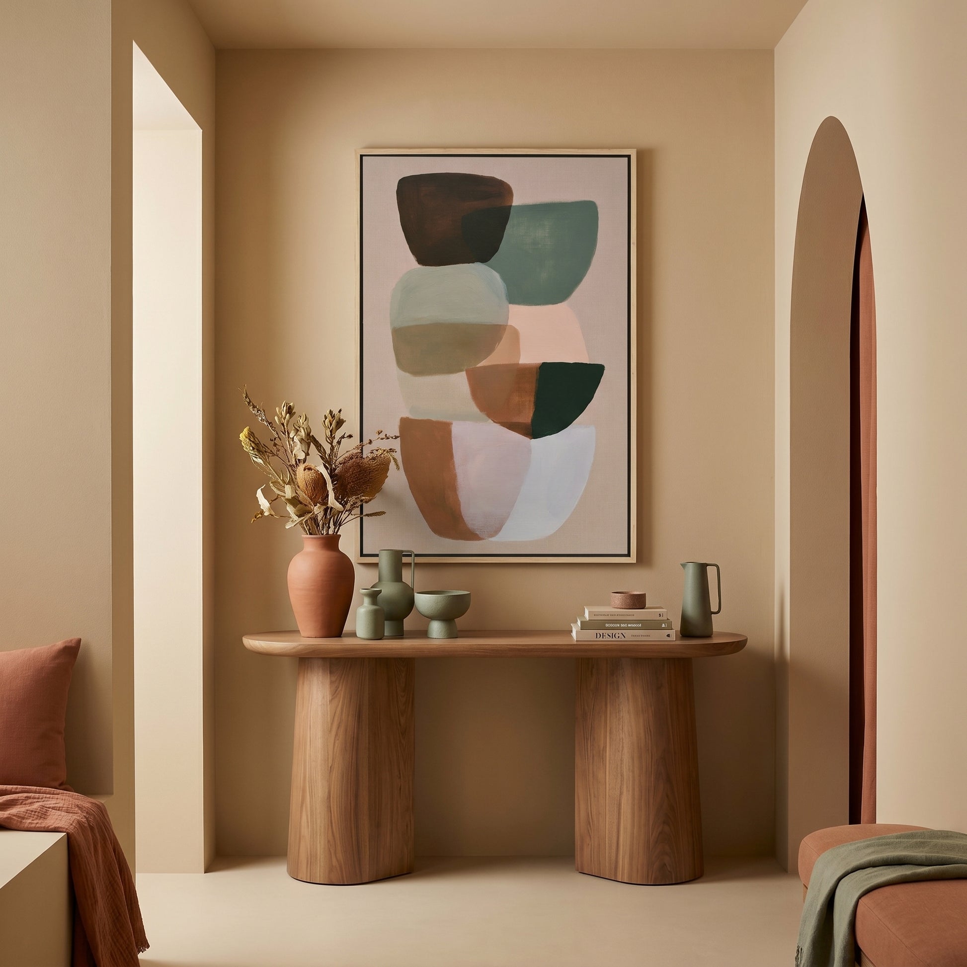 a minimalist living room with a wooden console table, a framed abstract painting, and various decorative elements such as a vase with dried flowers and a stack of books.