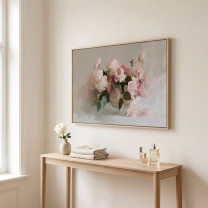 a wooden console table with a vase of white flowers, two bottles of perfume, and a framed painting of pink flowers hanging on the wall above it.