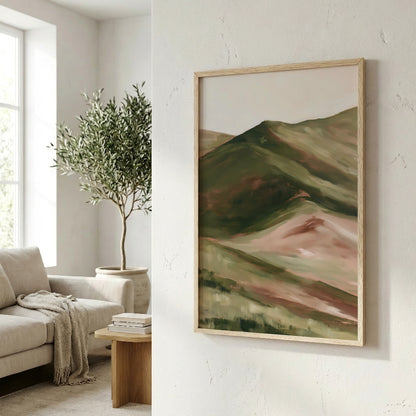 a living room with a large framed landscape painting hanging on the wall, depicting a mountain scene with green and brown tones. The room also includes a couch, a potted plant, and a wooden side table with books on it.