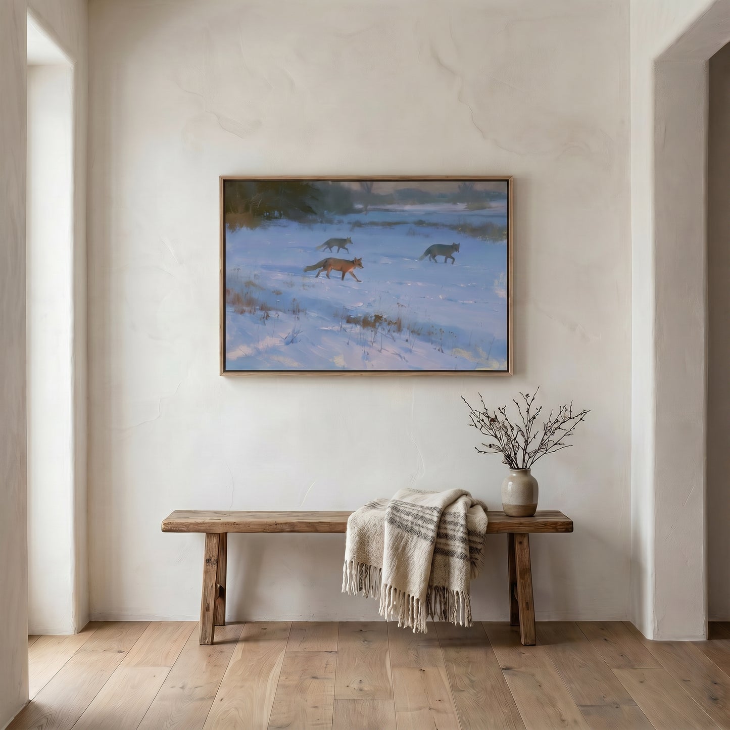 a wooden bench with a blanket draped over it, situated in a room with a large painting of two foxes on the wall above it.