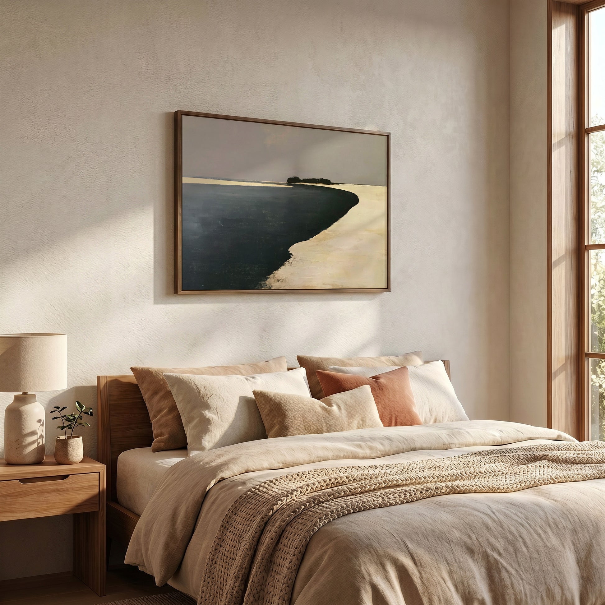 a serene bedroom scene with a large bed adorned with beige bedding and a framed landscape painting hanging above it. The painting features a beach scene with a calm body of water and a distant shoreline. The room is well-lit, with natural light streaming in from a window on the right side, creating a peaceful and relaxing atmosphere.