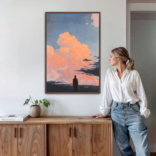 A woman in a white shirt and blue jeans stands in a room, leaning against a wooden cabinet, with a framed painting of a person standing in front of a cloudy sky hanging on the wall above her.