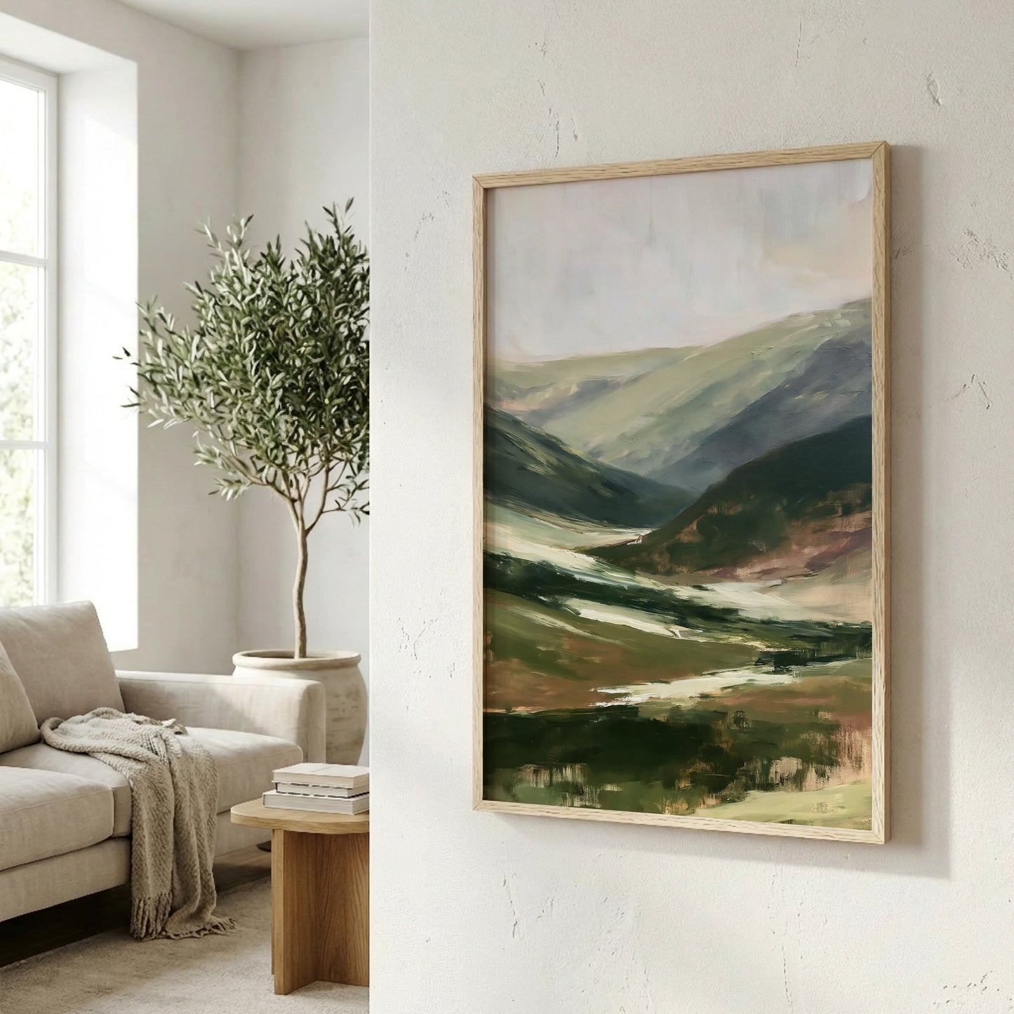 a living room with a large painting of a landscape hanging on the wall, a sofa, a potted plant, and a wooden side table.